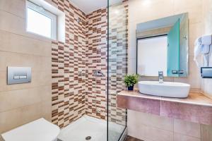 拉加纳斯Yakinthos Hotel的一间带水槽和玻璃淋浴的浴室