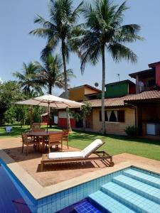 伊利亚贝拉Suíte Água Branca Residencial Exclusive的游泳池配有桌椅、桌子和遮阳伞