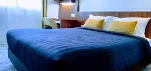 吉隆坡UTM Hotel & Residence的一间卧室配有一张带黄色枕头的大型蓝色床
