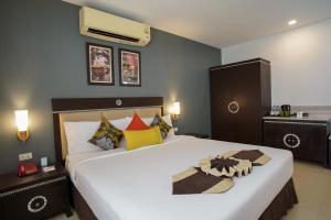 曼谷Club Mahindra Mac Boutique Hotel的卧室配有一张带彩色枕头的大型白色床。