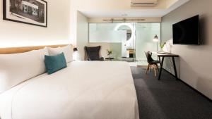 惠灵顿Hotel Room @ 89 Courtenay Place的卧室配有一张白色大床和一张书桌