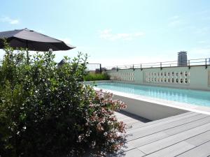 巴塞罗那Hotel Raval House的大楼内带遮阳伞的游泳池