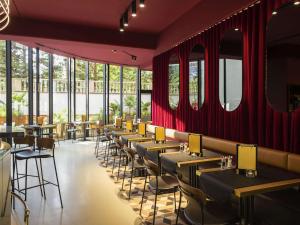 布鲁塞尔都会大酒店的一间设有桌椅的餐厅,位于带窗户的房间内