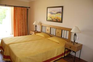 珀彻斯Apartamento T1 - Praia Senhora da Rocha的一间卧室配有一张床、两盏灯和一个窗户。