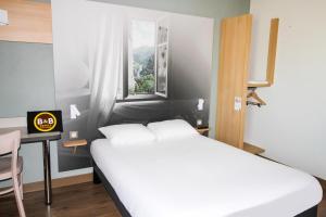 阿利仙B&B HOTEL Valence TGV Romans的一间卧室配有一张床、一张桌子和一个窗户。
