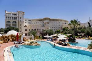 哈马马特麦地那日光浴及海水浴酒店的一座带大型游泳池的度假村,位于一座建筑前
