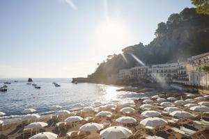 陶尔米纳Villa Sant'Andrea, A Belmond Hotel, Taormina Mare的一群在海滩上靠近水面的遮阳伞