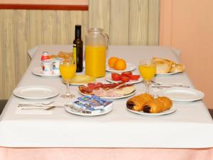 瓦德诺比斯Hotel Querol的餐桌,带食物盘和橙汁杯