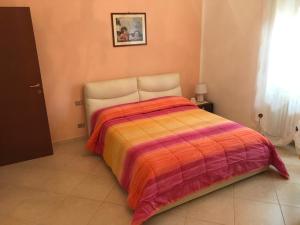 BussoLux Appartamento的一间卧室配有一张带橙色和紫色毯子的床
