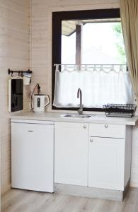 乌斯特卡A Morze Ustka的厨房配有白色橱柜、水槽和窗户。