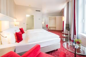 比勒费尔德Steigenberger Hotel Bielefelder Hof的卧室配有一张白色大床和红地毯
