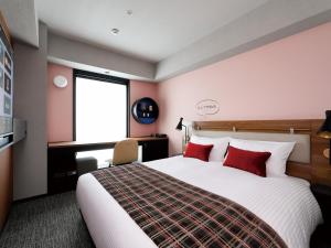 大阪DEL style Osaka Shin Umeda by Daiwa Roynet Hotel的一间卧室配有一张带红色枕头的大床