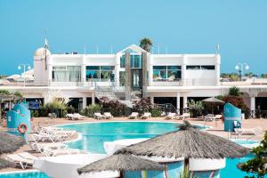 普拉亚布兰卡普拉亚布兰卡俱乐部酒店的一个带椅子和遮阳伞的游泳池的度假酒店