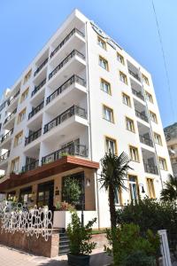 圣金Carpe Diem Apartments-Hotel的一座白色的大建筑,前面有一棵棕榈树