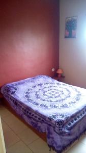 萨利波图尔Auberge Le Baobab的卧室内的一张床铺,配有紫色和白色的被子