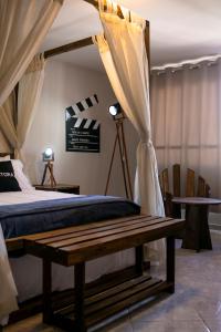 多明戈斯马丁斯Pousada Rua de Lazer的一间卧室设有一张天蓬床和一张木凳
