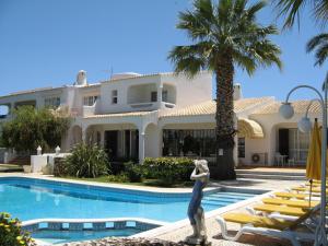 卡武埃鲁橄榄农场酒店的一座带游泳池和棕榈树的大型白色房屋