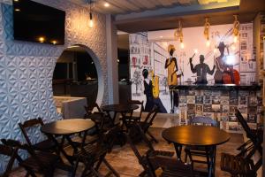马拉巴INACIO'S PLAZA HOTEL的一间带桌椅的餐厅以及一个带壁画的墙壁