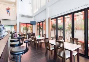 卡马拉海滩Buk Inn Hotel SHA Plus的餐厅设有桌椅和窗户。