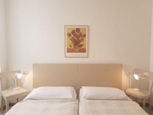 托尔博莱Casa Sandra Bertolini Appartamenti的卧室配有两张床,墙上挂着一幅画