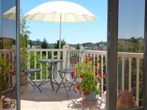 萨尔拉拉卡内达Maison Pierre D'Or的阳台配有桌子和雨伞。