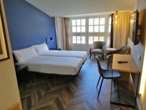 拉科鲁尼亚Hotel Alda Galería Coruña的酒店客房带一张床、一张桌子和椅子