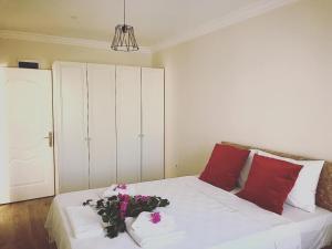 伊兹密尔Apart TU Çeşme的一张带红色枕头和鲜花的白色床