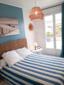 莱萨布勒-多洛讷Les portes du soleil的卧室配有蓝色和白色条纹床和窗户。