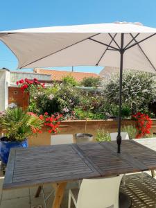 莱萨布勒-多洛讷Les portes du soleil的一张带雨伞和一些植物的木桌
