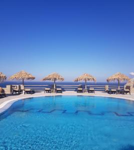 米克诺斯城戈尔戈纳酒店的一个带椅子和遮阳伞的游泳池以及大海