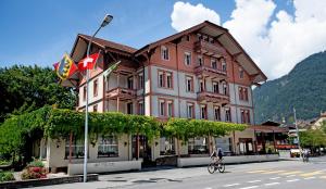 因特拉肯Hotel Sonne Interlaken-Matten的一个人在建筑物前骑着自行车