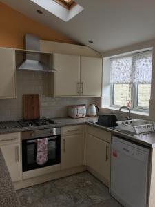 什鲁斯伯里Primrose的厨房配有白色橱柜和炉灶烤箱。