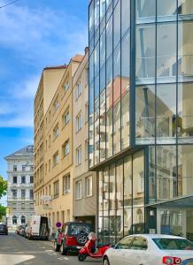 维也纳Luxurious city apartment incl garage and terrace的一座玻璃建筑,前面有汽车停放