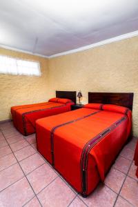 危地马拉安地瓜Hotel La Sin Ventura的红色床单的客房内的两张床