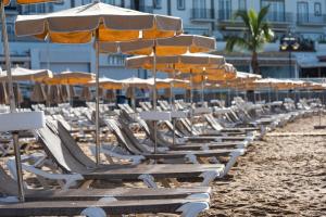 莫甘海滩Apartamentos Las Palmeras的海滩上的一排躺椅和遮阳伞