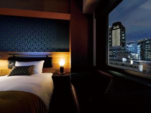 大阪DEL style Osaka Shin Umeda by Daiwa Roynet Hotel的一间卧室配有一张床和一个享有城市天际线的窗户。