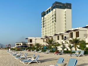 迪巴Mirage Bab Al Bahr Beach Hotel的海滩上一排高楼躺椅