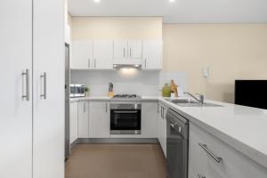 悉尼The Banq Apartments by Urban Rest的白色的厨房设有水槽和炉灶。