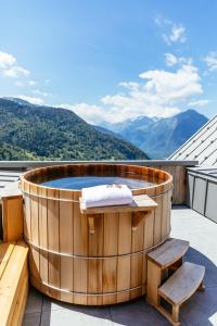 沃雅尼Hotel Le V de Vaujany的屋顶上的热水浴池,以山脉为背景