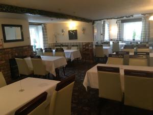 奥斯威斯The New Inn的用餐室配有桌椅和白色桌布