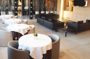 奥佩拉米兰高尔夫酒店的餐厅配有白色的桌子、沙发和椅子