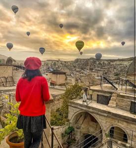 格雷梅阿伊迪尼尔岩洞酒店的站在阳台上看到热气球的女人
