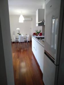 科米索Biancaura sunlight的厨房配有白色橱柜和一张带白色椅子的桌子