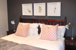 白河Heuglins Lodge的一间卧室配有带粉色和白色枕头的床