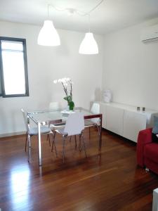 科米索Biancaura sunlight的一间设有玻璃桌和白色椅子的用餐室
