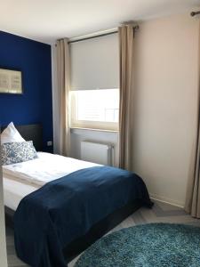 亚琛bensons hotel的一间卧室配有一张蓝色墙壁的床和一扇窗户