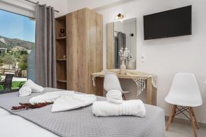 卡拉马孔Antonis apartments的一间卧室配有一张带两把白色椅子的床和一台电视。