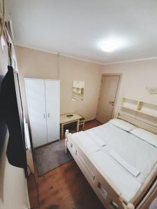 兹拉蒂博尔Guest House Colovic的卧室配有一张白色大床和一张书桌