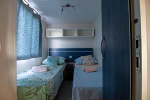 斯里马Mobile homes Bonaca的配有两张蓝色墙壁和粉红色枕头的客房内的床铺