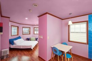 平昌CHAEUL Pension的粉红色的客房配有一张床、一张桌子和椅子